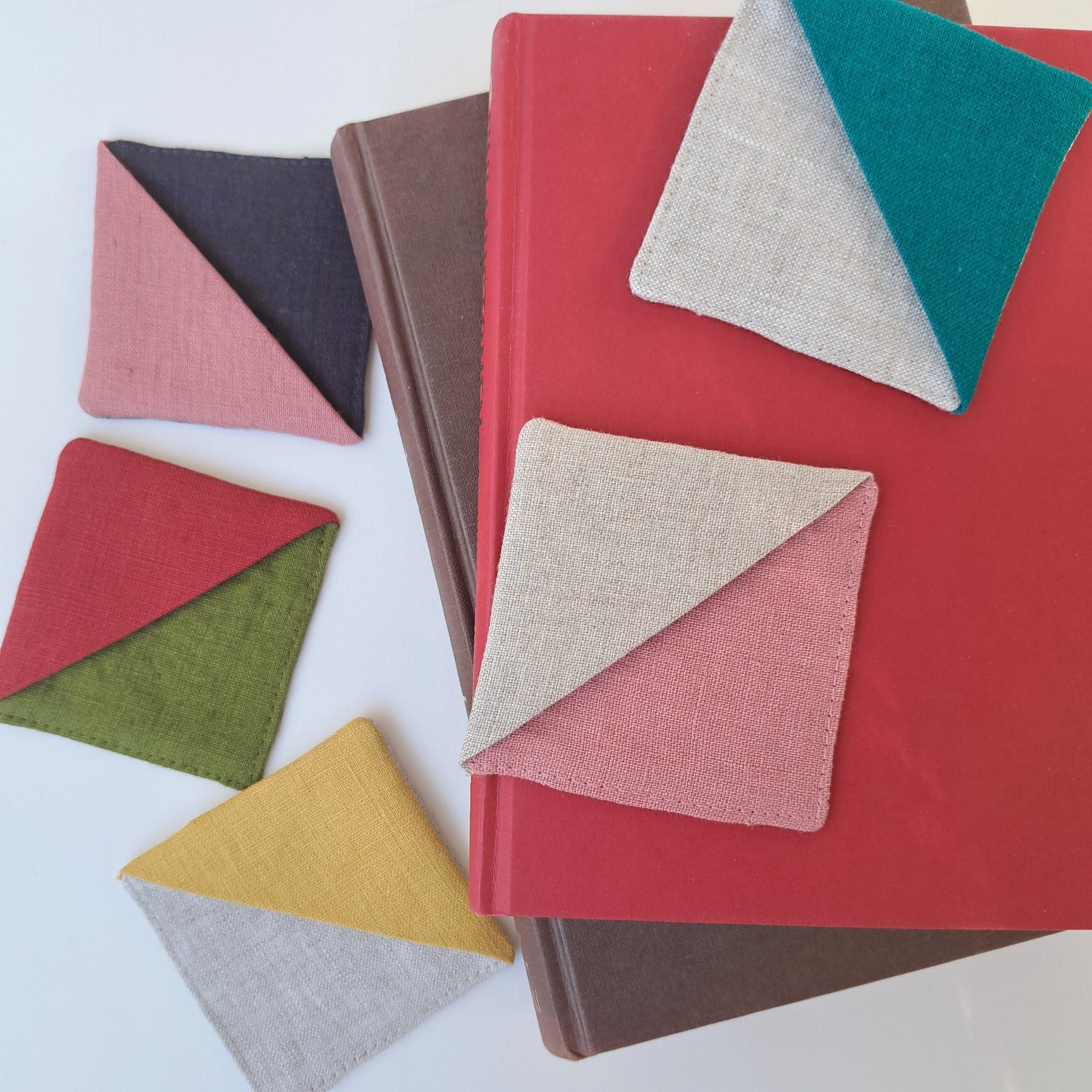 Kulmakirjanmerkkejä monessa värissä pöydällä ja kirjojen päällä.